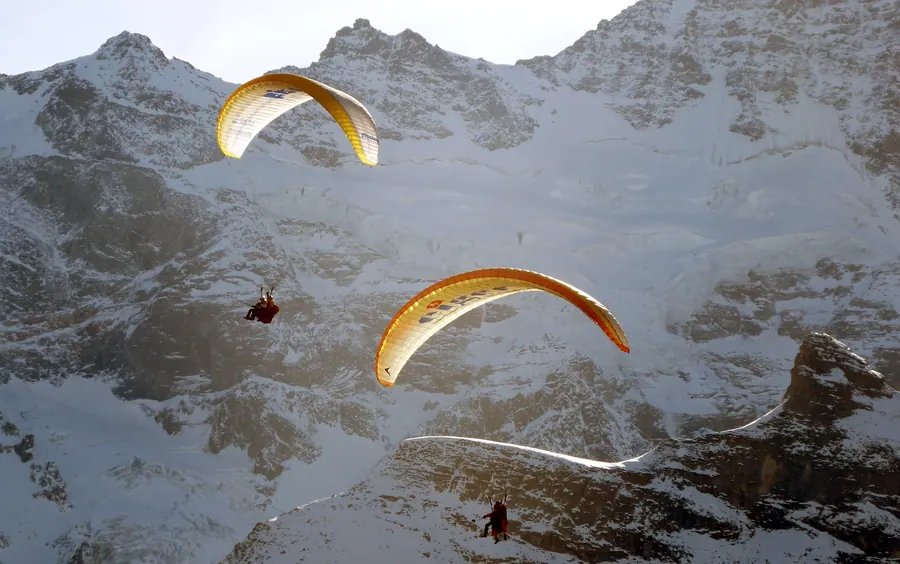 Zwei Tandem-Gleitschirme vor einer Felswand bei Mürren