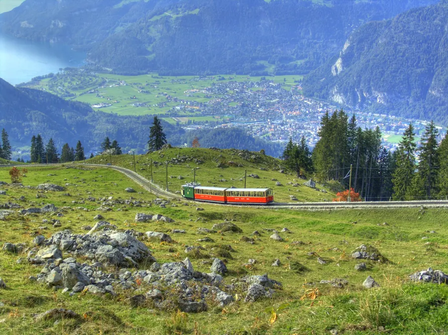 Ein Zug der Schynige Platte-Bahn auf der Alp, tief unten Interlaken