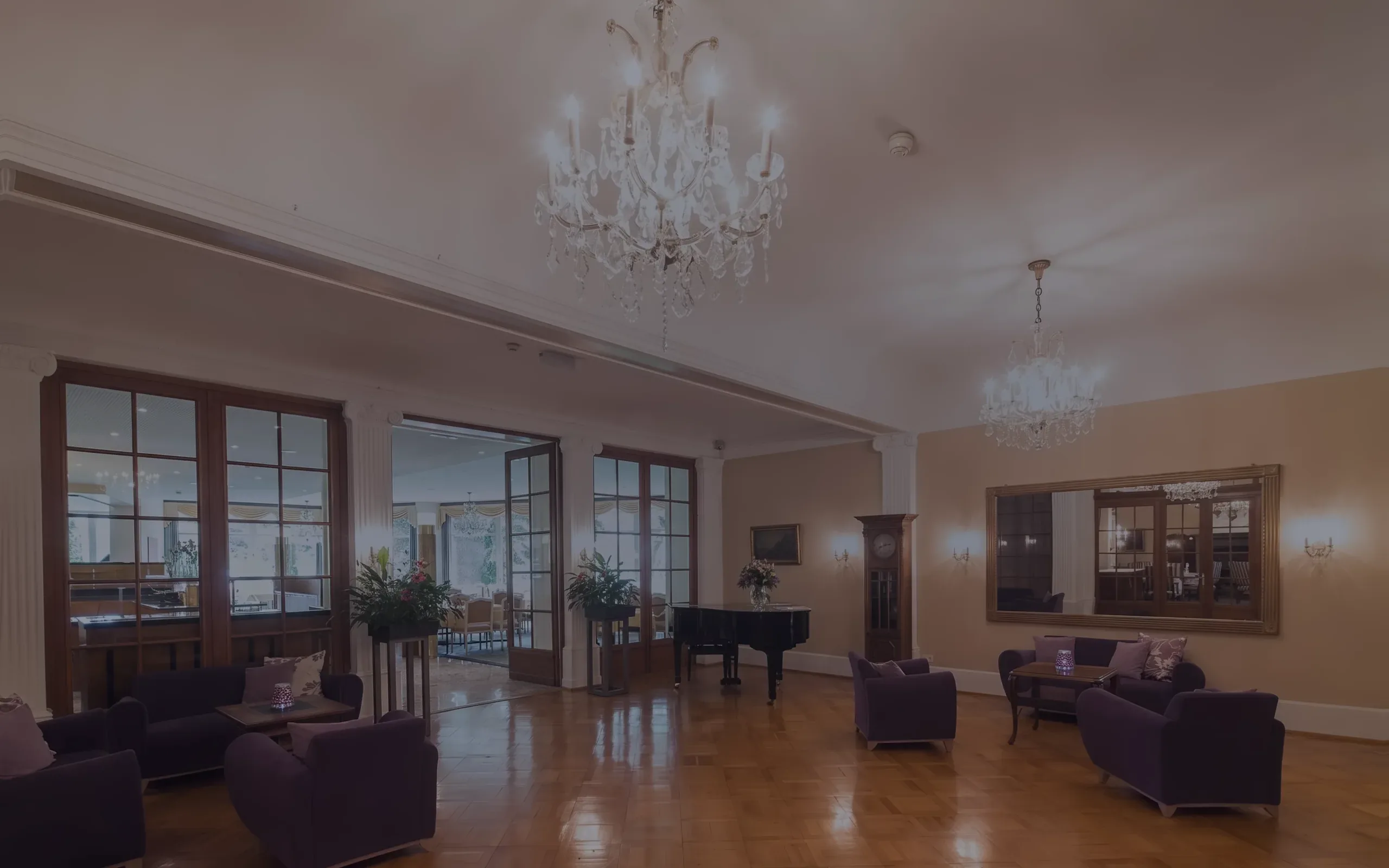 Ein Salon mit Kronleuchtern, Sesseln und einem Flügel