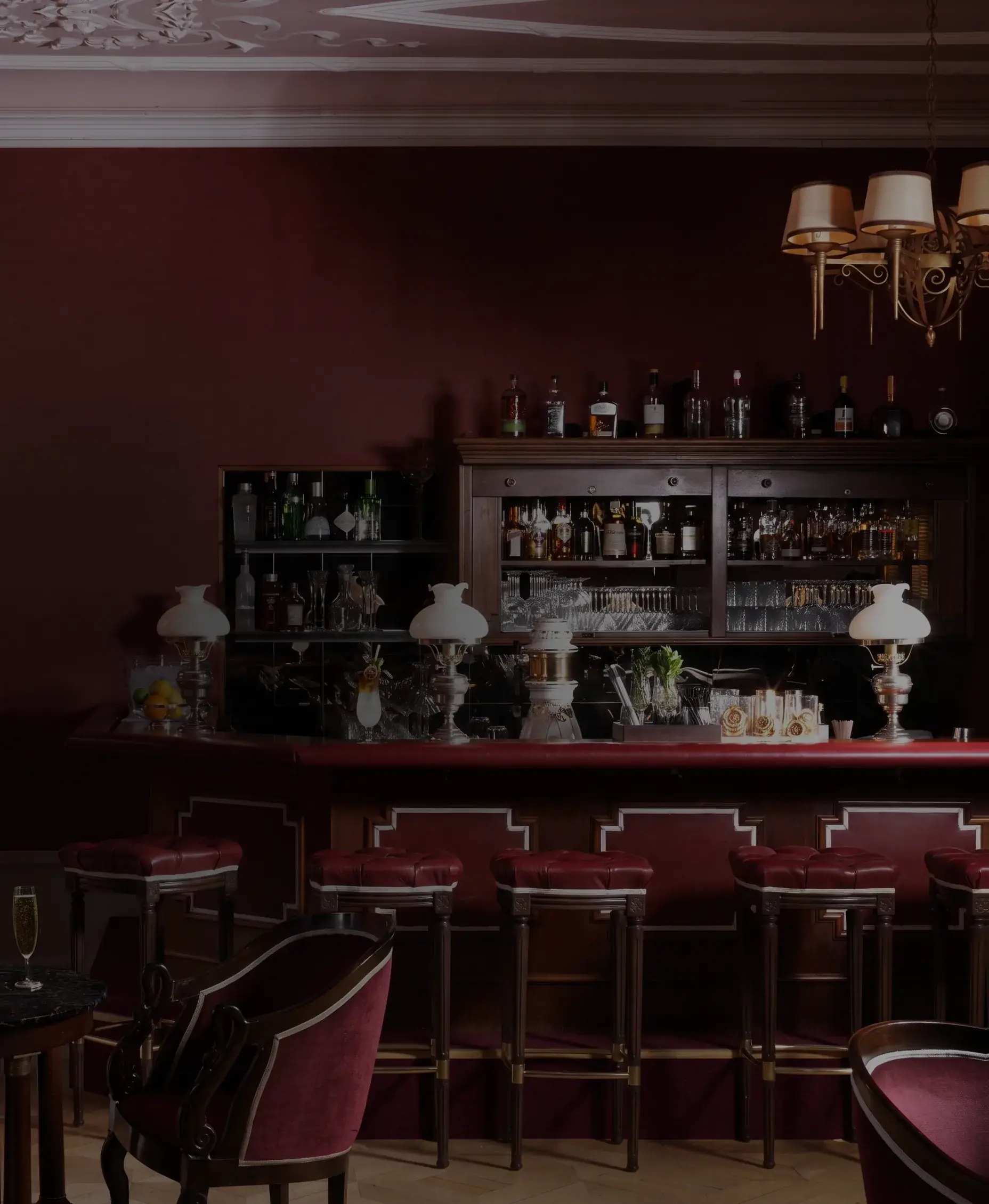 酒吧 «Le Vieux Rivage» 的吧台,红色高脚凳与枝形吊灯