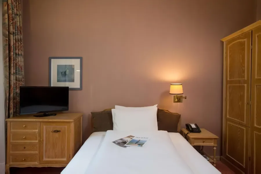 Einzelzimmer mit Bett und Holzschrank
