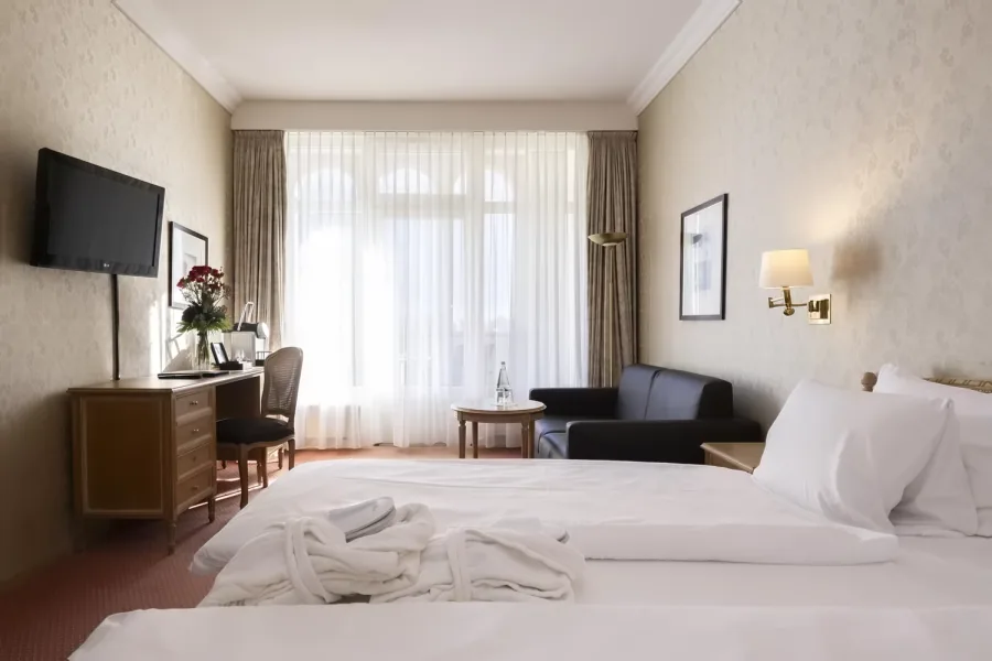 Doppelzimmer mit Sitzecke, Schreibtisch und hohem Fenster